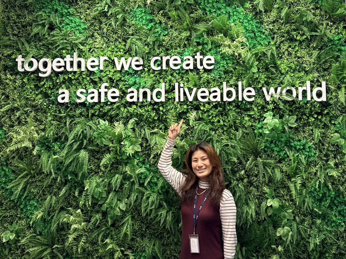 Rhea at Fugro, pointing at the company motto wall